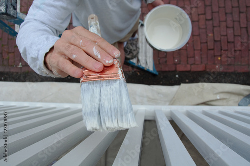 Painter Applying Paint to Exterior Balusters of Home