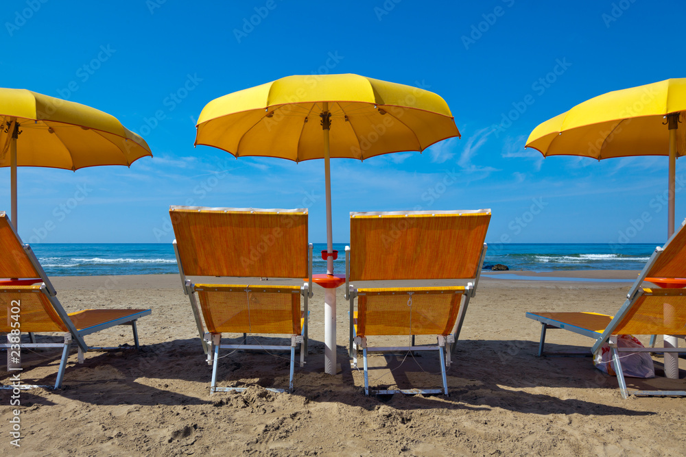 Lounge chairs under a yellow umbrella