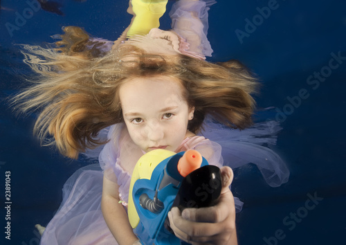 underwater portrait of girl with watergun in swimming pool photo