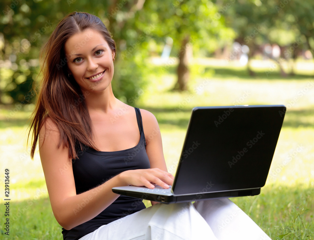 Beautiful young woman sits on a grass in a park with the laptop. Beautiful young woman sits on a grass in a park with the laptop.