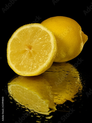 Lemon on the black background with water drops photo