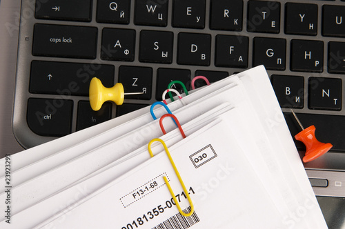 Paper documents with clips on laptop keyboard