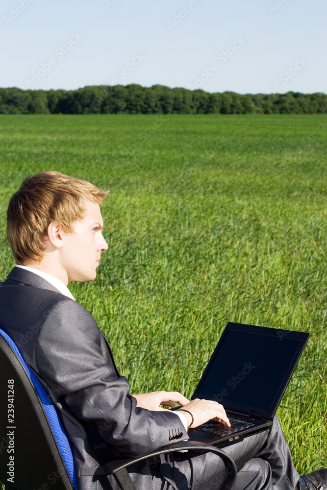 Businessman in the field, with a laptop. Pensive man Businessman in the field, with a laptop. Pensive man