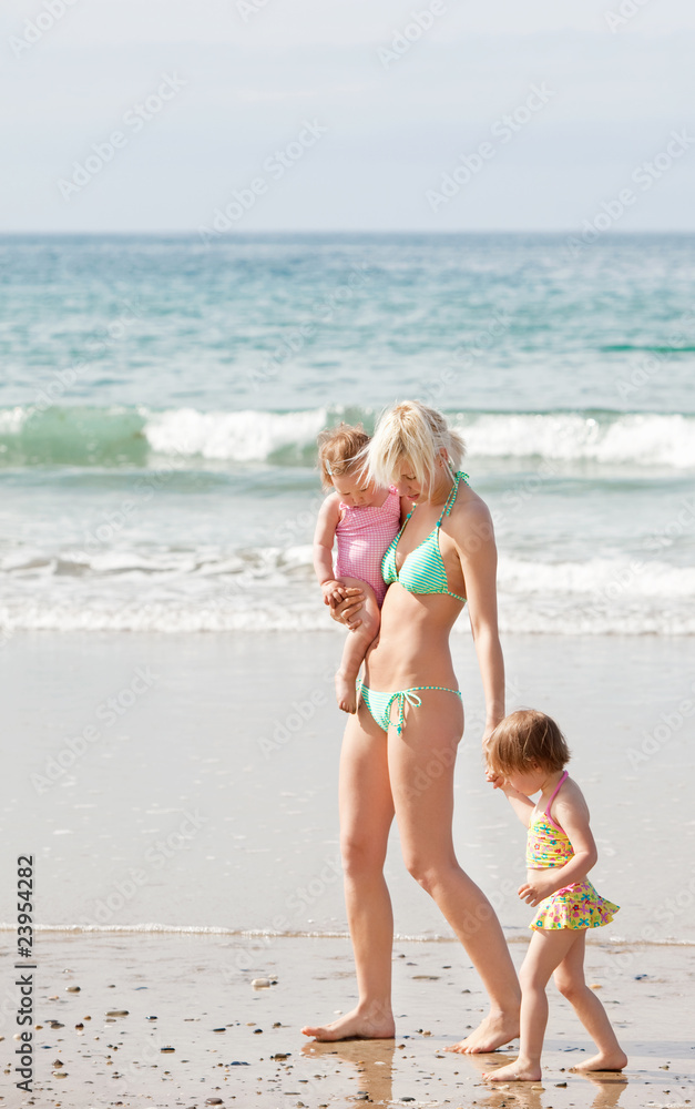 A young mother walking at the beach with her children A young mother walking at the beach with her children