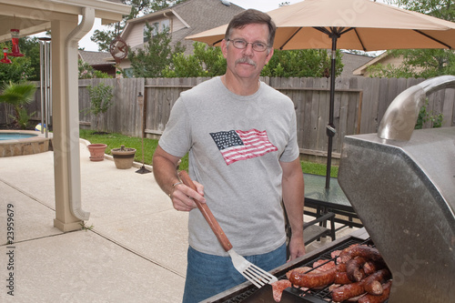 Young man barbecuing hamburgers and sausages