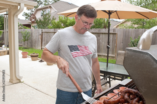 Young man barbecuing hamburgers and sausages
