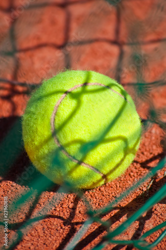 Tennis ball behind the green net.