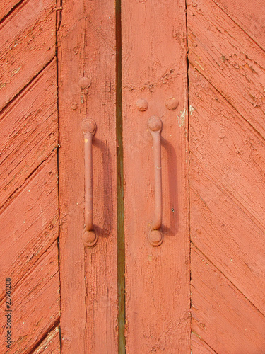 Old red wooden barn doors with metallic handles.
