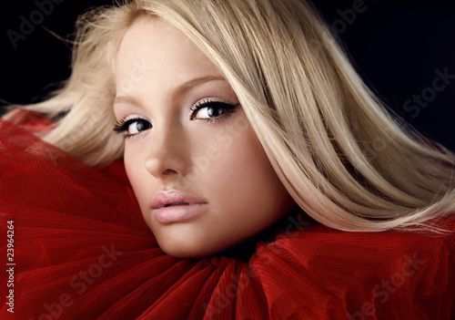 Foto Attractive blond beauty in a red theatrical jabot. Close-up Port
