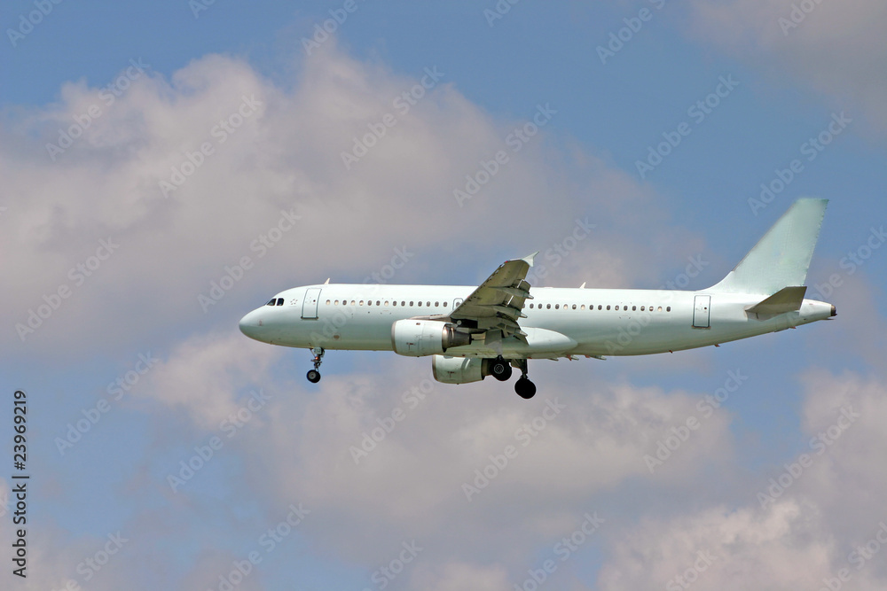 A landing airplane with blue sky and clouds background.