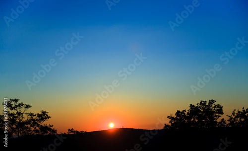 wounderful sunset with sun and siluet of trees and mountains