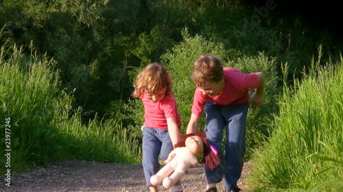 brother and sister holds doll and runs in park