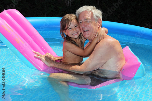 Valokuva Grandfather and granddaughter cuddling on a lilo in a pool
