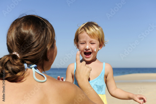 Mother applying sunscream to her happy child