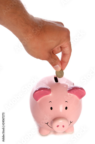 Man putting pound coin in piggybank