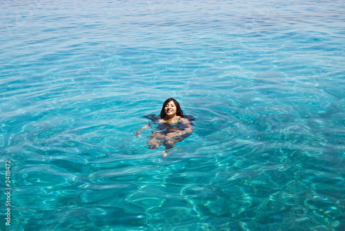 A beautiful indian woman swimming in turquoise blue sea.