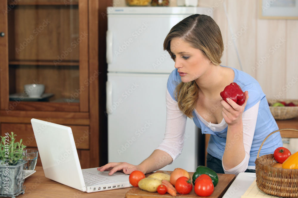 Jeune femme devant un ordinateur portable dans la cuisine Jeune femme devant un ordinateur portable dans la cuisine