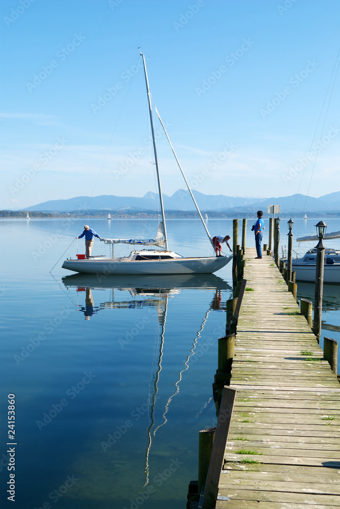 A couple prepare their sailing boat in Chiemsee lake pier