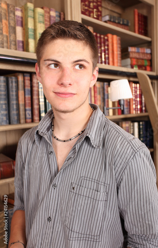 young student dreaming in front of a book shelf