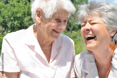 Two elderly women laugh, outdoors
