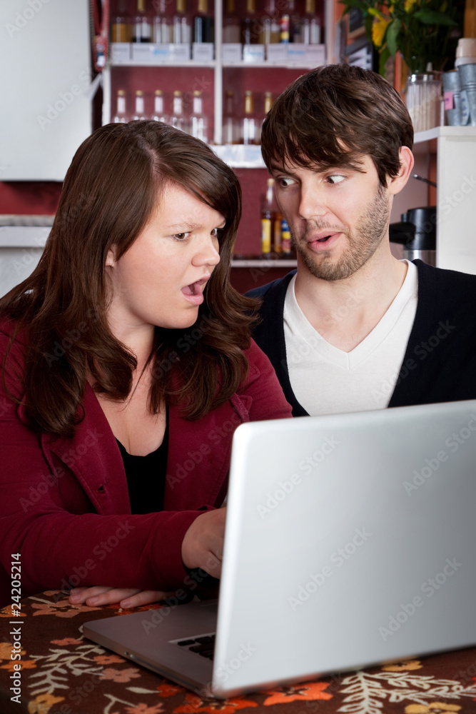 Woman and man staring in disbelief at a computer laptop Woman and man staring in disbelief at a computer laptop