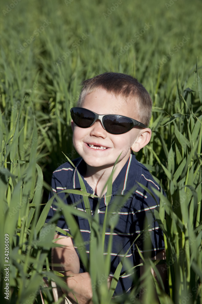 boy with sunglasses in tall oat field