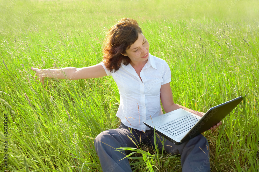 Young woman working on laptop in the field Young woman working on laptop in the field