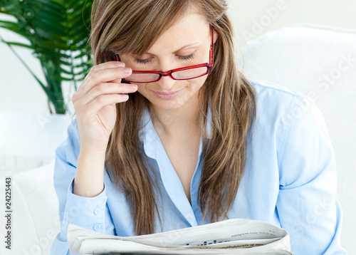 Enthusiastic woman with glasses reading a newspaper photo