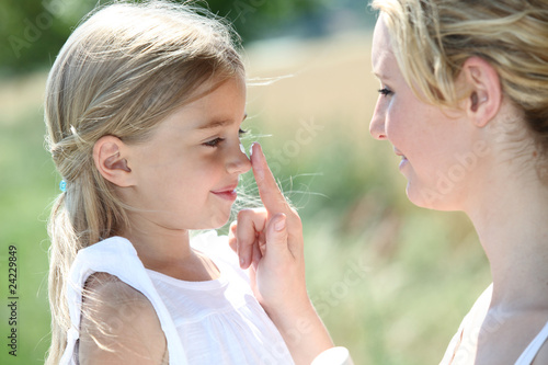 Mother and daughter putting sunscreen on their face