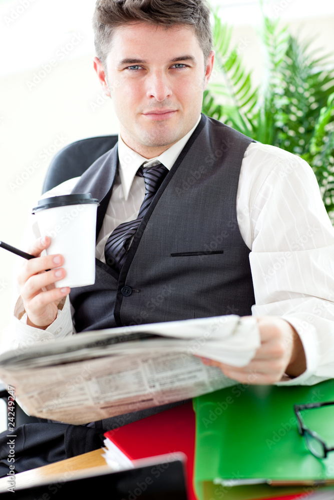 Serious businessman drinking a coffee while reading a newspaper Serious businessman drinking a coffee while reading a newspaper