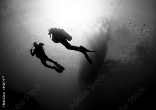 scuba divers silouetted by sun ball