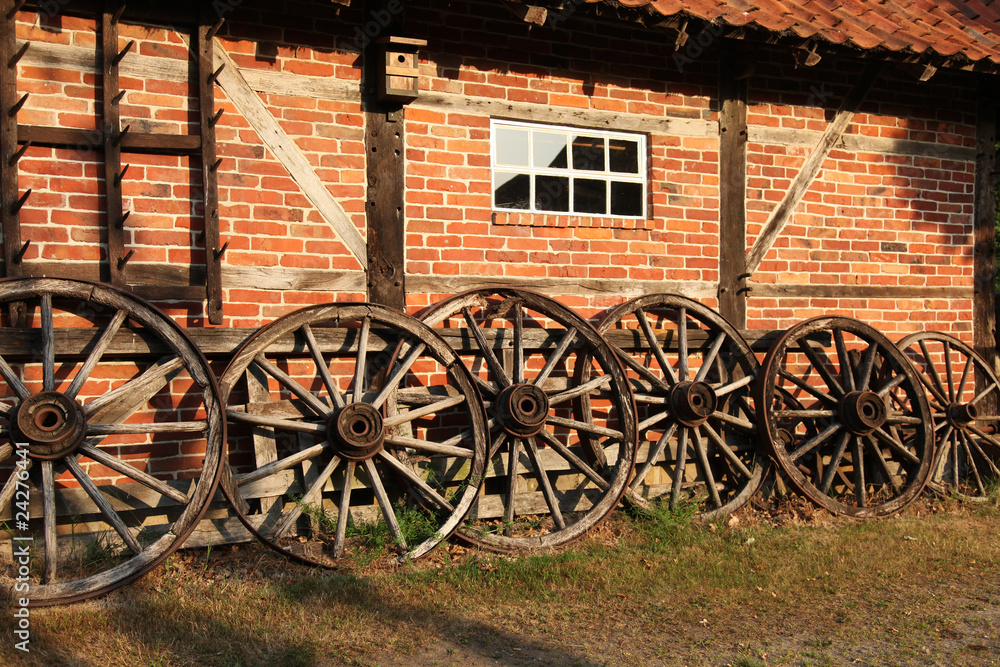 Alte Wagenräder vor einem Fachwerk