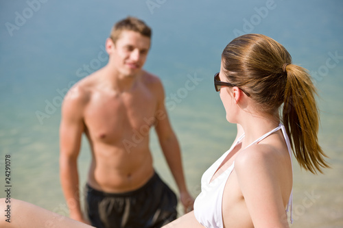 Woman in bikini sunbathing by sea on beach