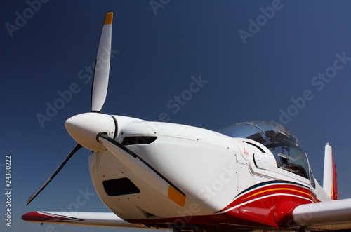 Motorflugzeug in Weiss-Rot-Blau vor blauem Himmel