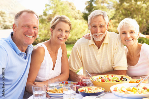 Adult Son And Daughter Enjoying Meal In Garden With Senior Paren