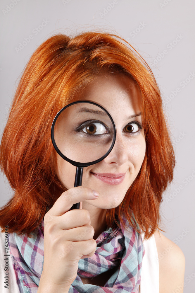 Beautiful red-haired girl with loupe zooming her eye. Beautiful red-haired girl with loupe zooming her eye.