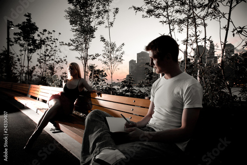 Canvas Print Young attractive couple sit next to each other on a park bench