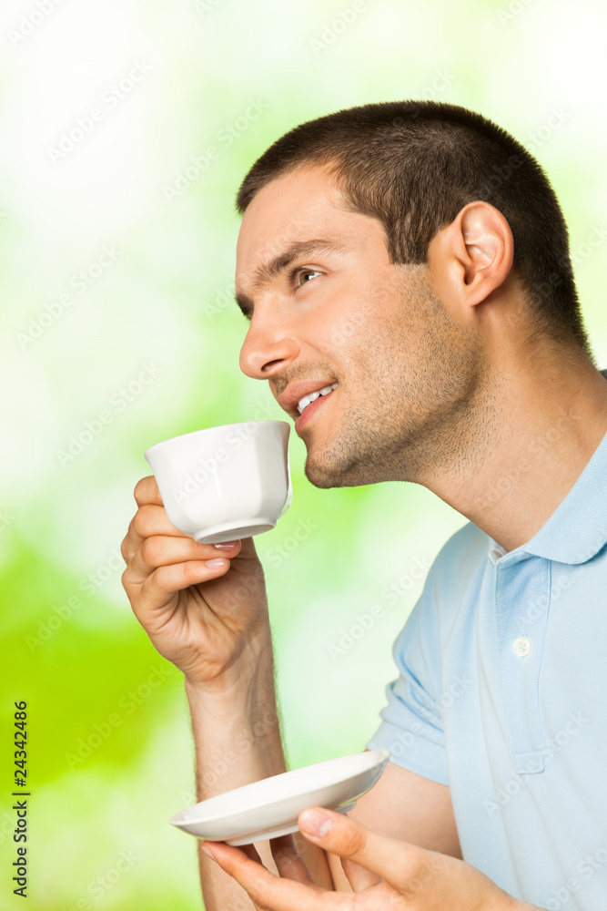 Young happy smiling man drinking coffee, outdoors Young happy smiling man drinking coffee, outdoors
