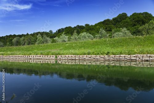 Ufer am Fluss Isar mit grünem Gras und blauem Himmel