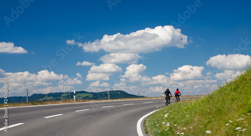 two bicyclists on road with a perfect sky