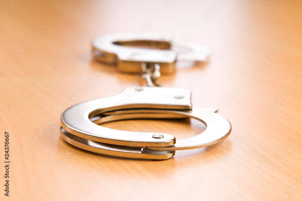Metal handcuffs on the wooden background Metal handcuffs on the wooden background