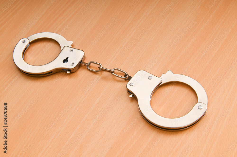 Metal handcuffs on the wooden background Metal handcuffs on the wooden background