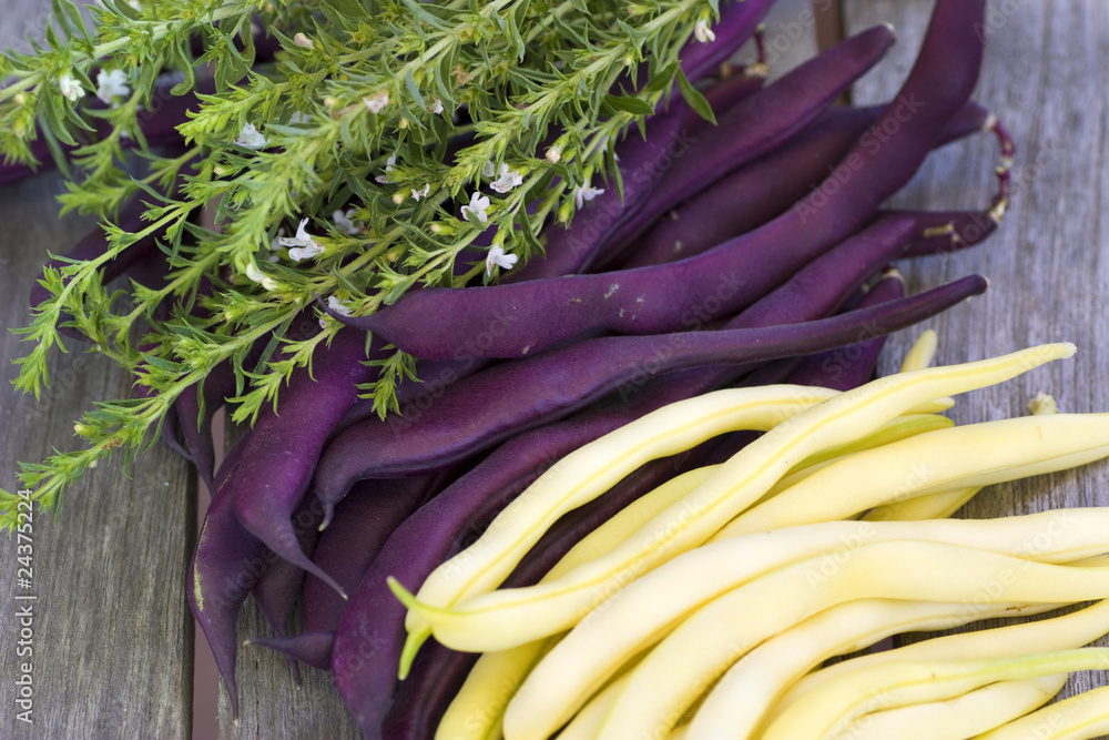 Purple and yellow beans lying on a wooden table