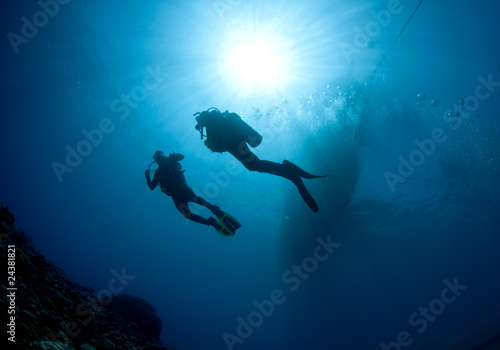 scuba divers silouetted by sun ball © JonMilnes