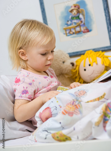 little girl in bed reading book