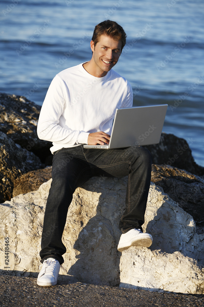 Young man using laptop at beach