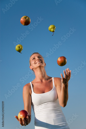 junge frau jongliert mit gesundem essen