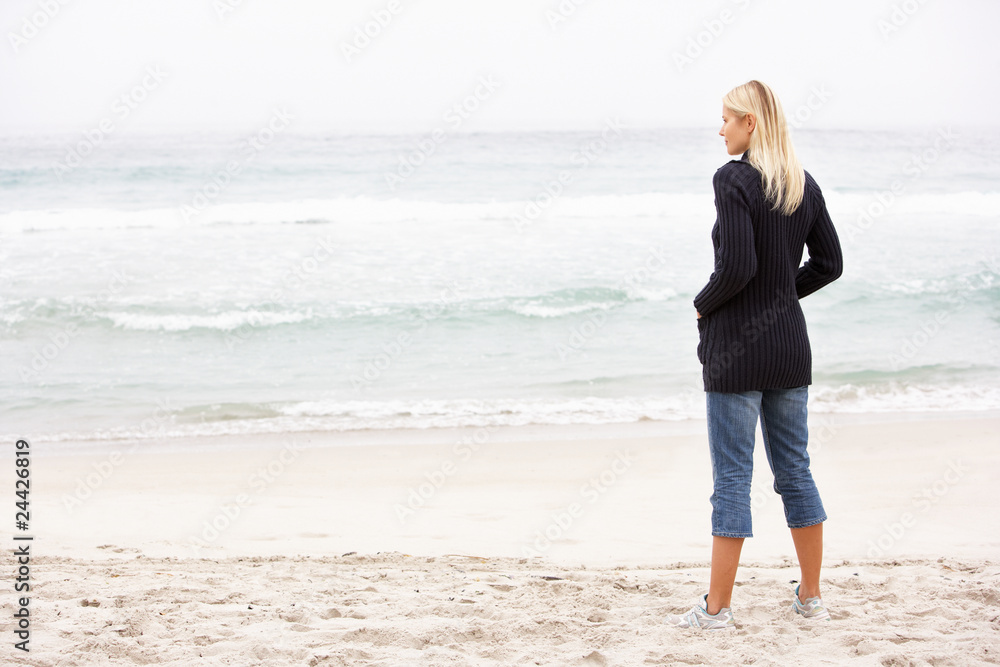 Young Woman On Holiday Standing On Winter Beach
