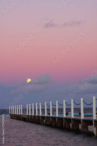 Full moon rising over the ocean at sunset