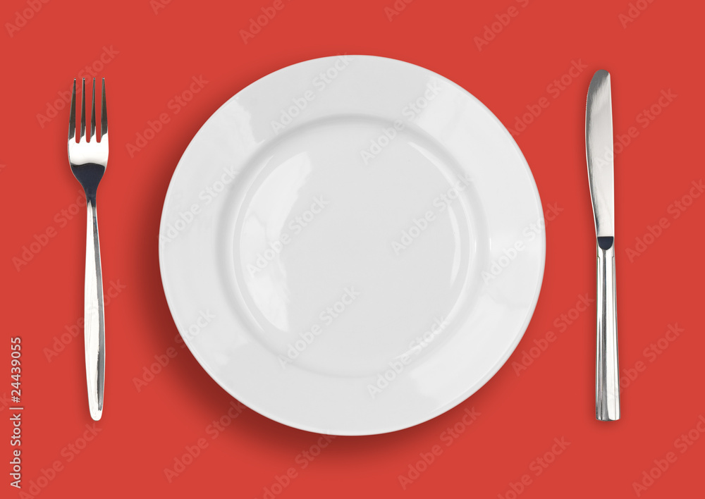 Knife, white plate and fork on red background Knife, white plate and fork on red background